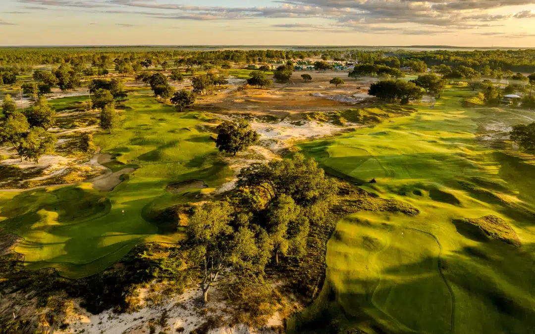 An aerial view of 'The Squeeze' golf course at Cabot Citrus Farms. The landscape is hilly, noted by green grass, sand pits and pine trees.
